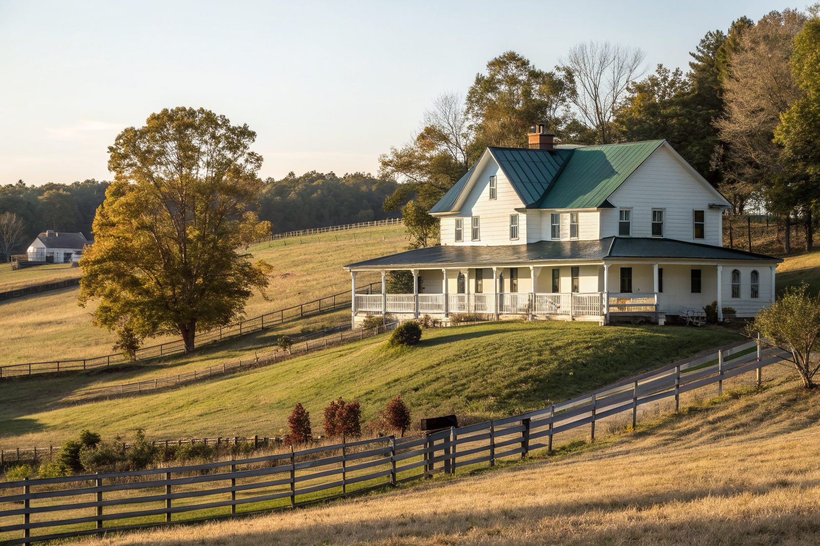 A white farmhouse with a dark green standing-seam metal roof on a pasture hill